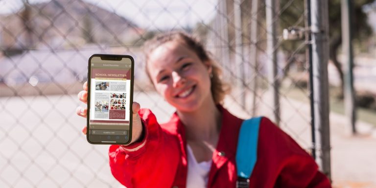 student-showing-school-newspaper-on-a-phone